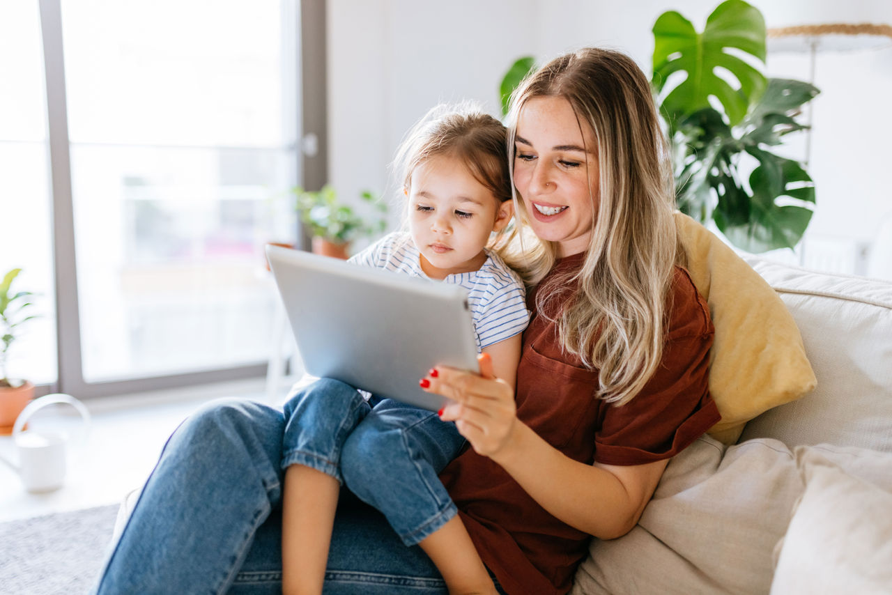Mother and daughter sitting together looking at a tablet